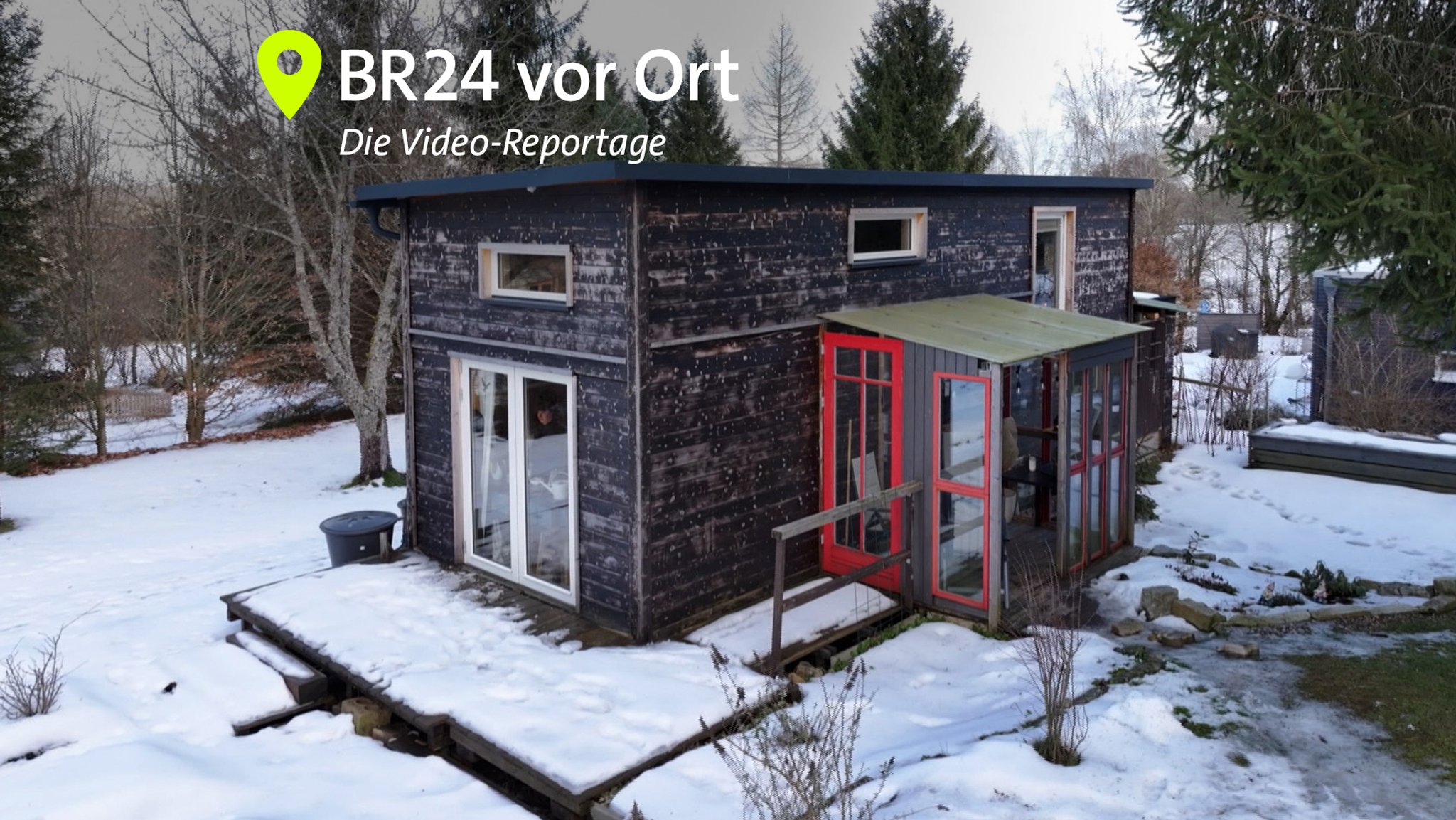 Ein kleines Holzhaus mit Flachdach steht auf einem verschneiten Grundstück, im Hintergrund sind Bäume zu sehen. | Bild: BR Ein kleines Holzhaus mit Flachdach steht auf einem verschneiten Grundstück, im Hintergrund sind Bäume zu sehen.