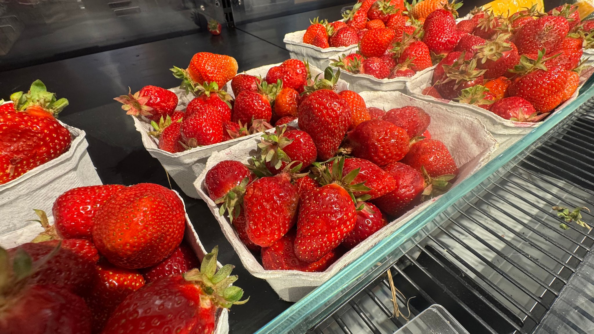 Mehrere Schalen Erdbeeren in einem Supermarkt-Regal